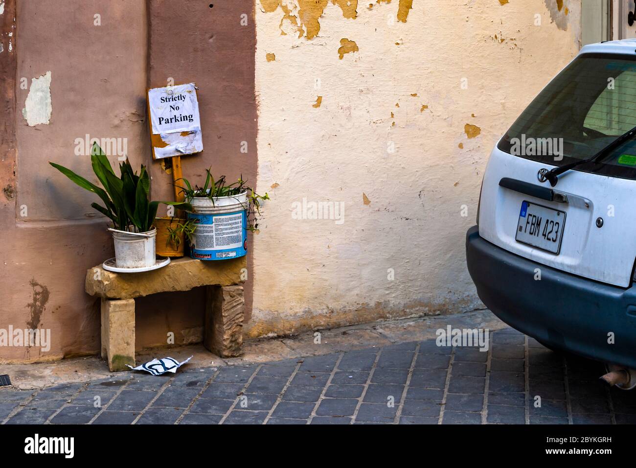 Tiny stone bench with planted buckets and the sign: parking strictly prohibited on Malta Stock Photo