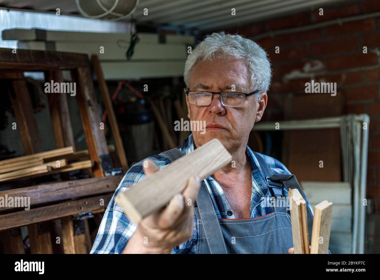 Old carpenter checking the wood planks. Stock Photo