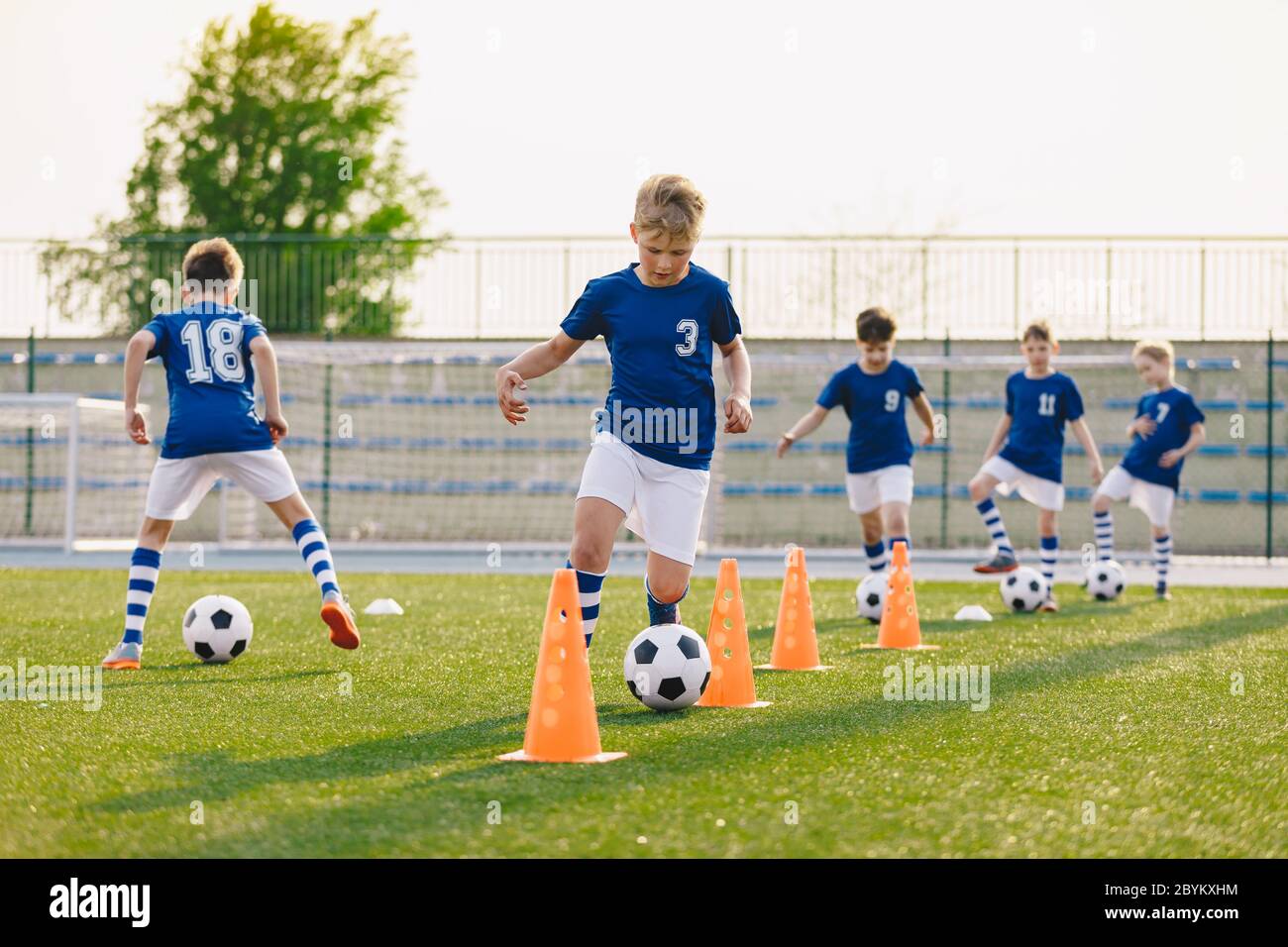 Soccer Training - Warm Up and Slalom Drills. Boys Practicing European Soccer on the Grass School Field Stock Photo