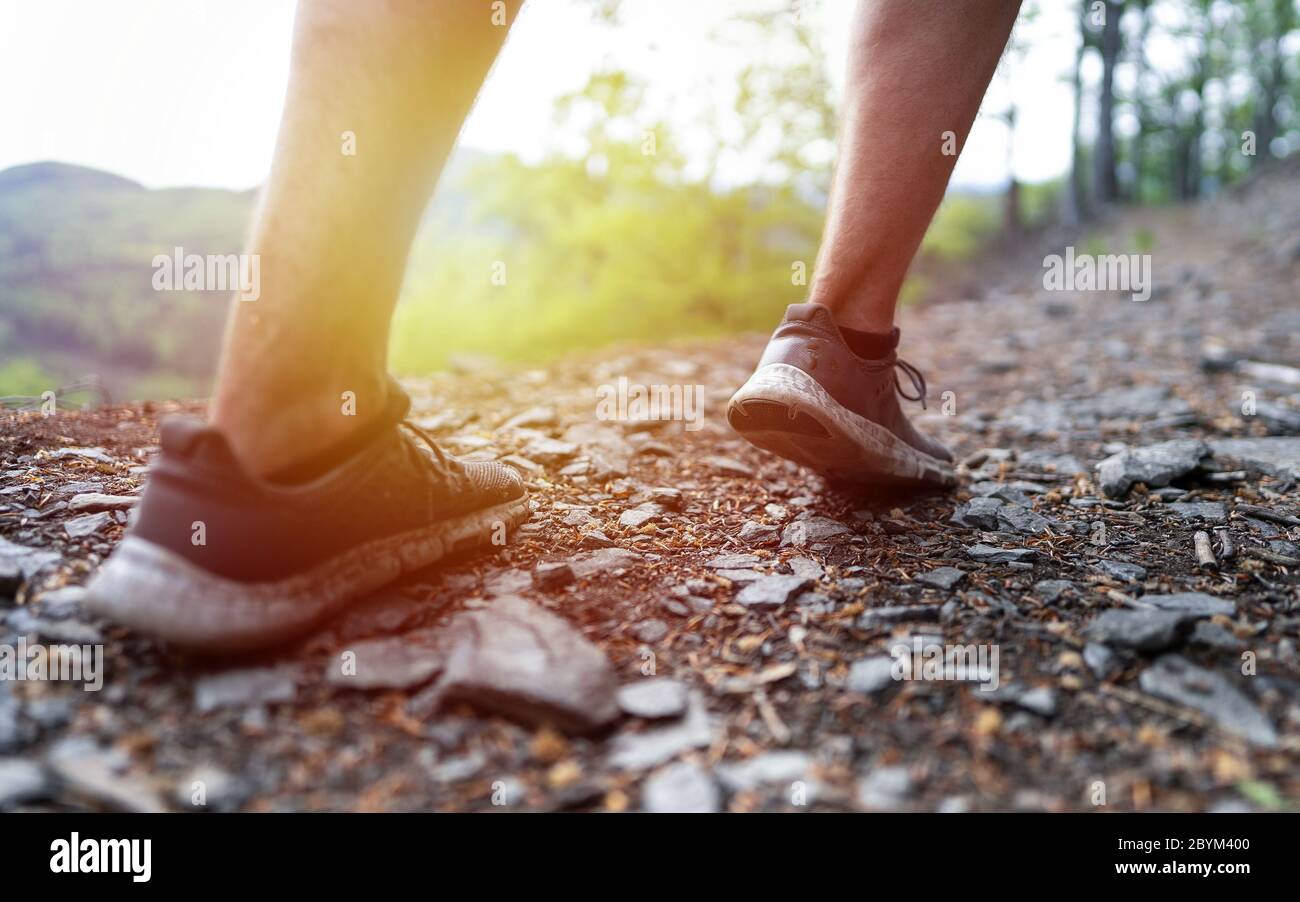 Close up male runner legs, muscular build man running fast. Trail