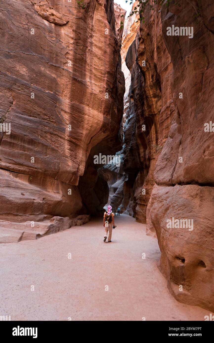 Photographer in a narrow stone gallery in Petra, Jordan. UNESCO world heritage site and one of The New 7 Wonders of the World. Stock Photo