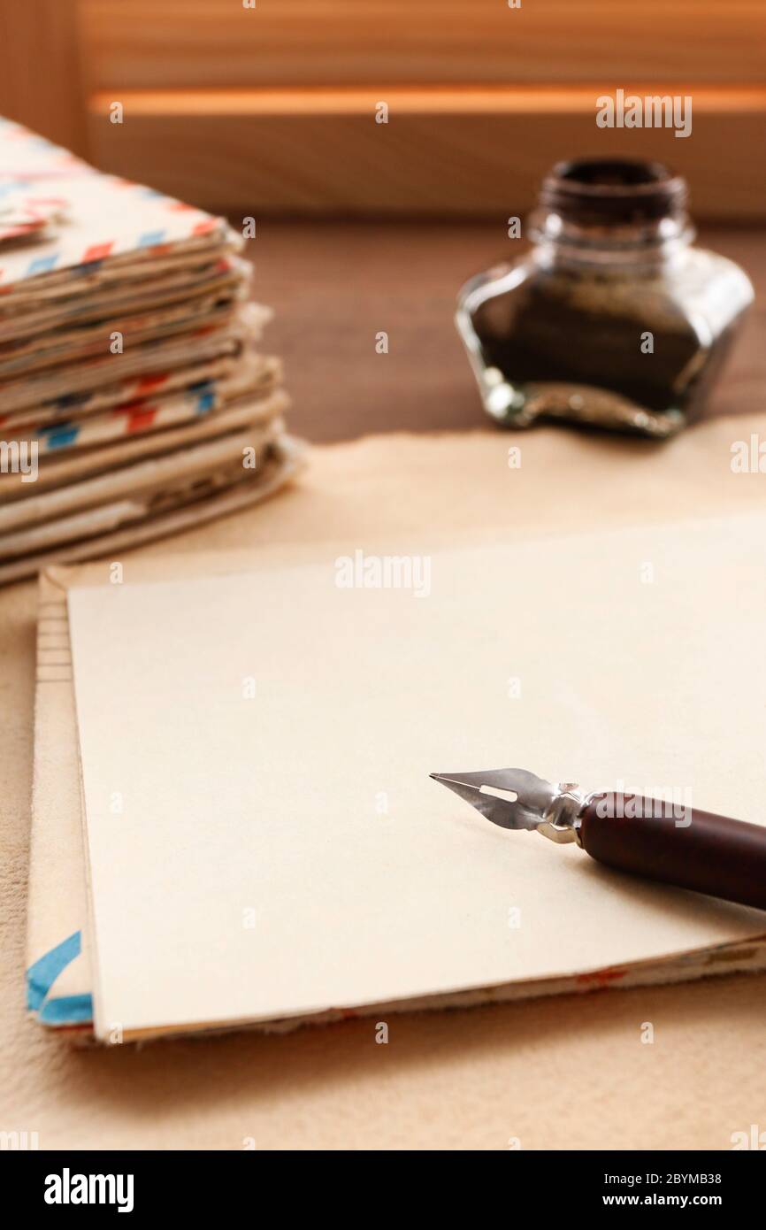 Stack of vintage letters, pen and inkwell on a wooden table. Romantic love letters concept. Stock Photo