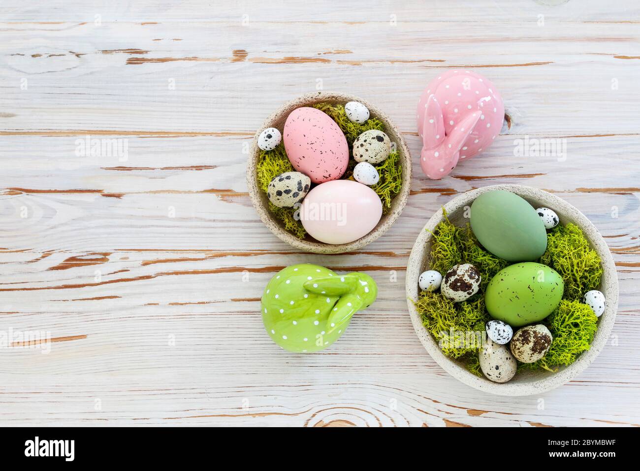 Easter decorations with eggs, moss and ceramic figurines on white wooden table. Festive time Stock Photo
