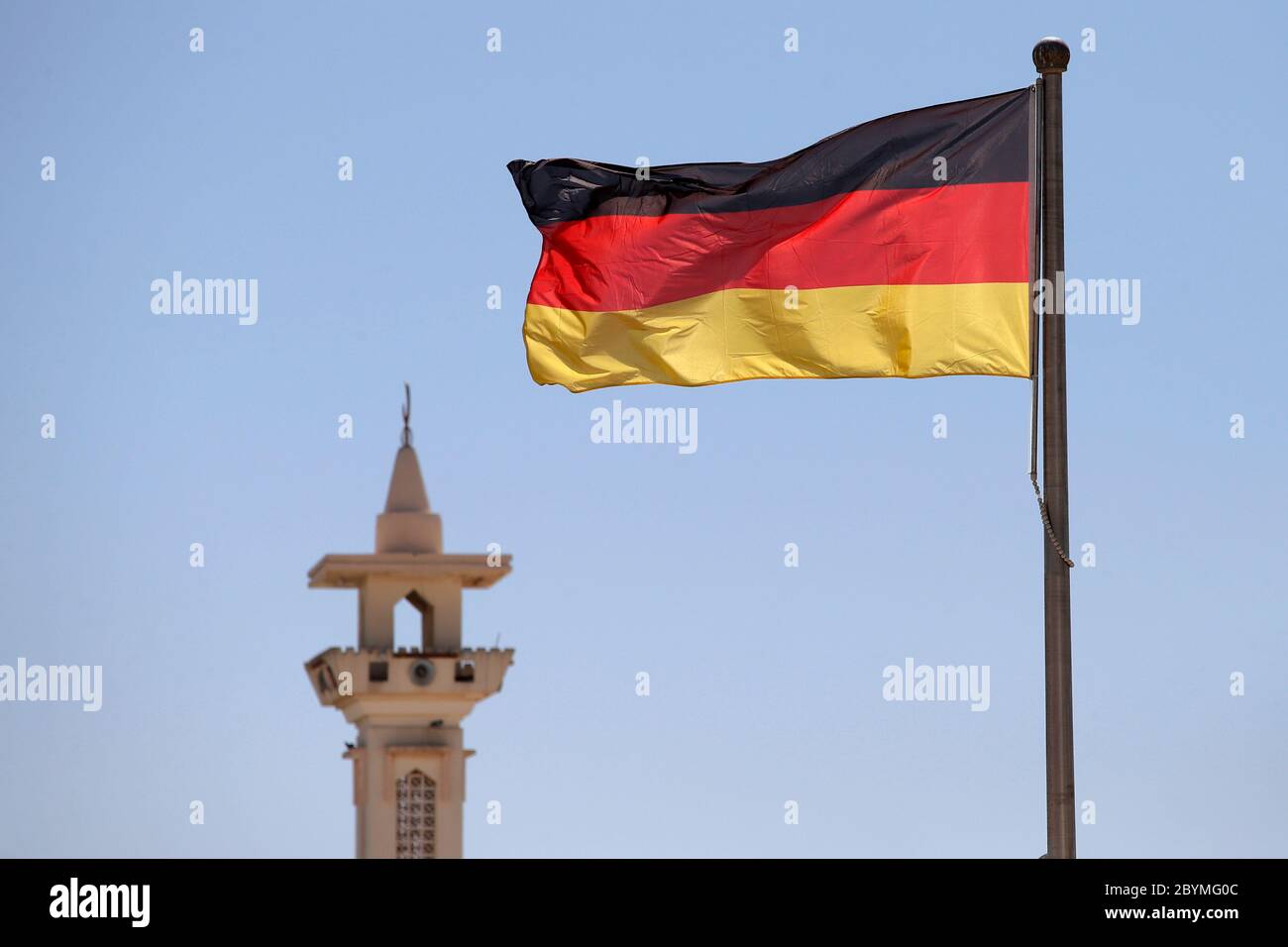 27.02.2020, Doha, , Qatar - National flag of the Federal Republic of Germany waving in front of a minaret. 00S200227D372CAROEX.JPG [MODEL RELEASE: NO, Stock Photo
