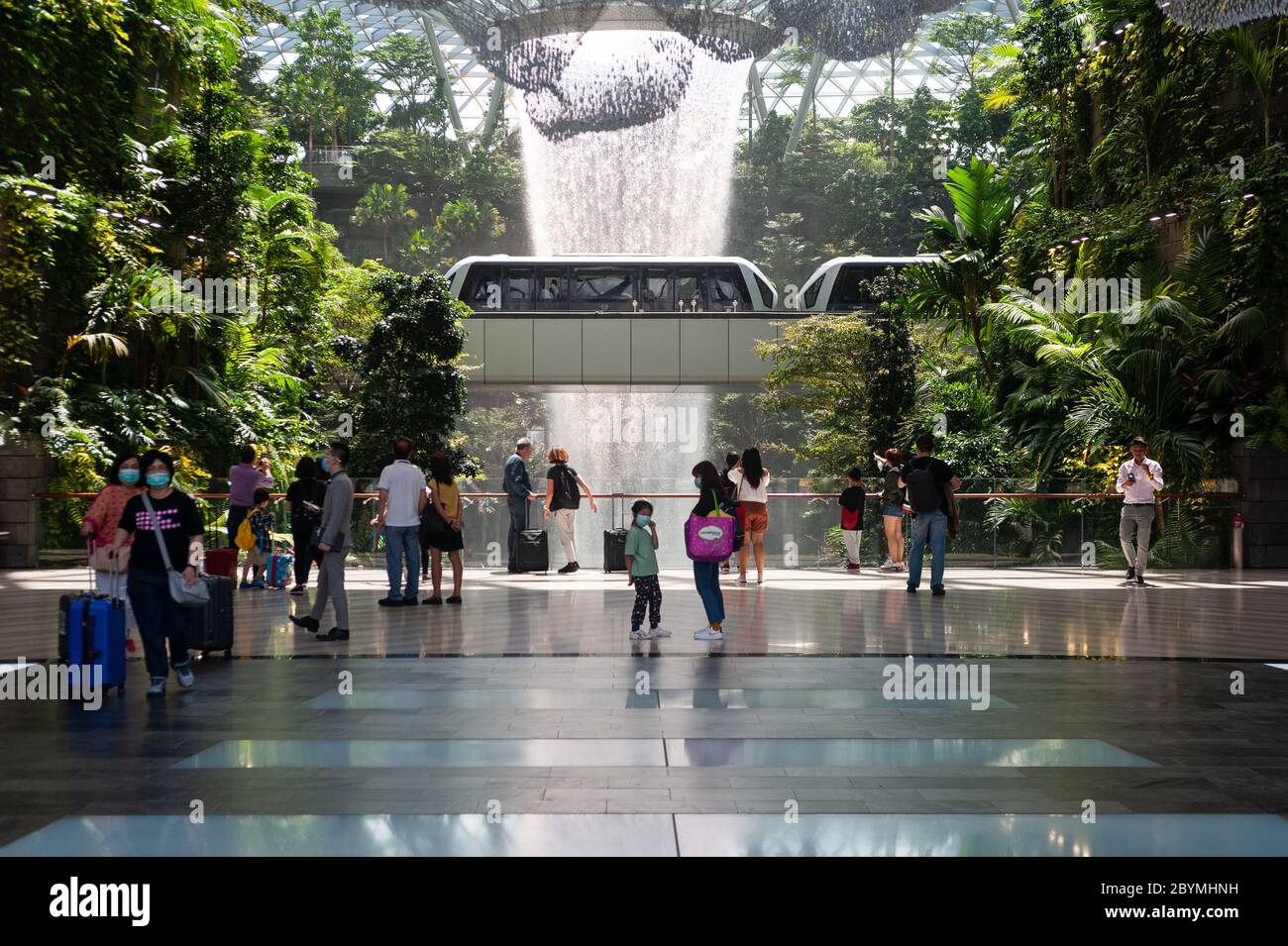 31.01.2020, Singapore, , Singapore - People in the new Jewel Terminal at Changi Airport in front of the rain whirlpool waterfall, wearing respiratory Stock Photo