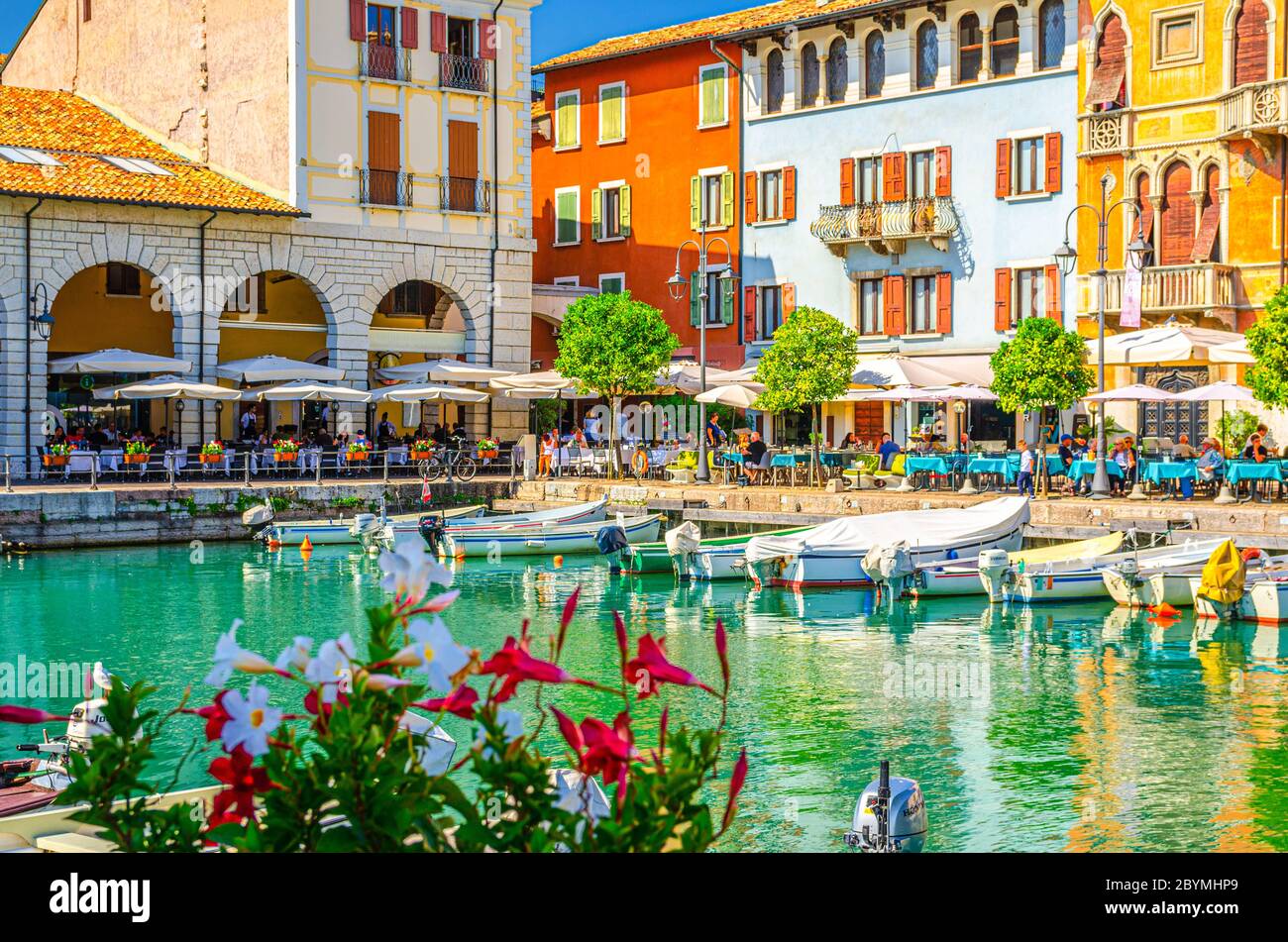 Desenzano del Garda, Italy, September 11, 2019: Old harbour Porto Vecchio with boats on turquoise water, street restaurants and traditional buildings in historical town centre, Lombardy Stock Photo