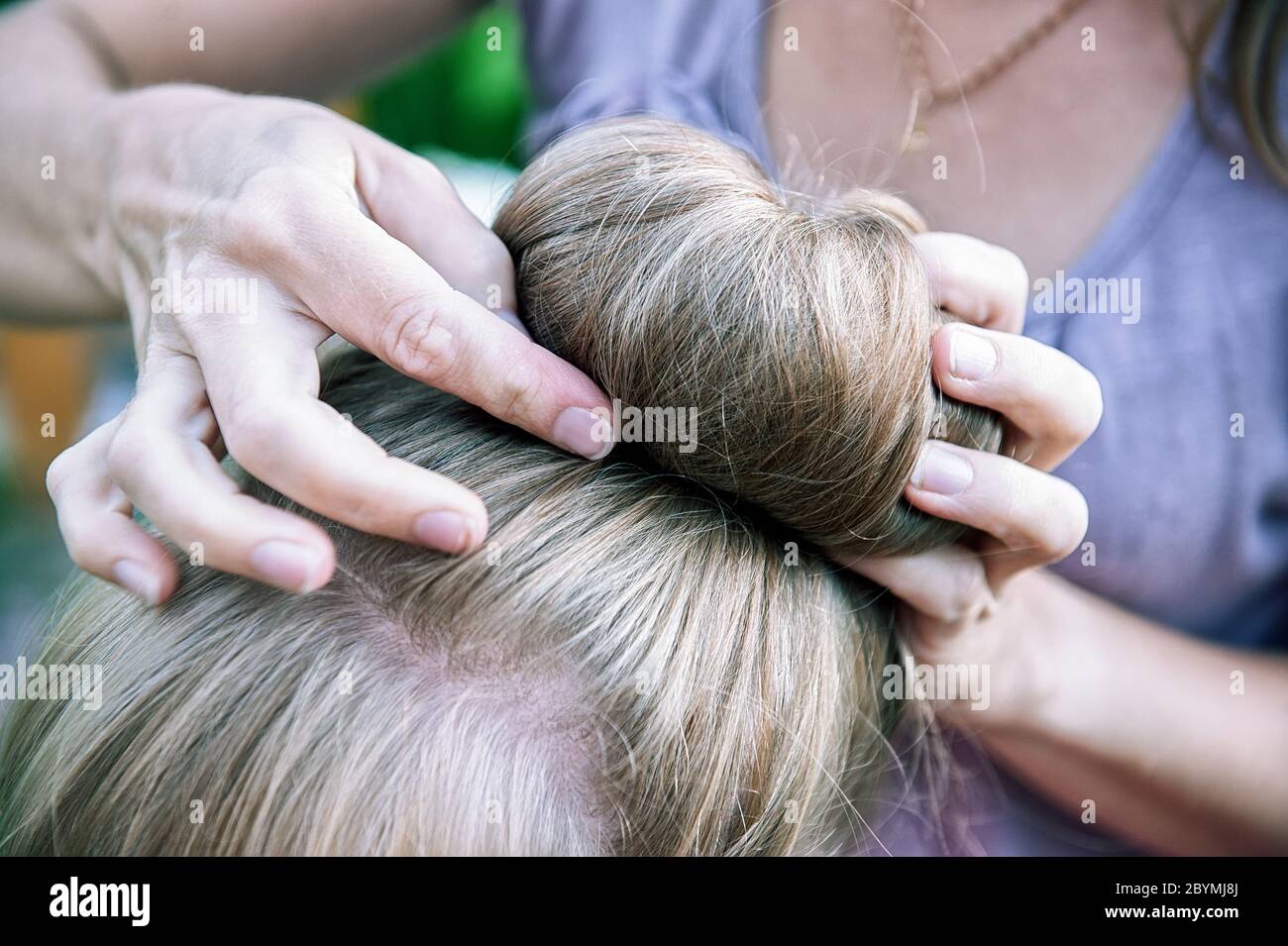woman's hands plait the girl's hair. A woman does her daughter's hair. Selective focus. Stock Photo
