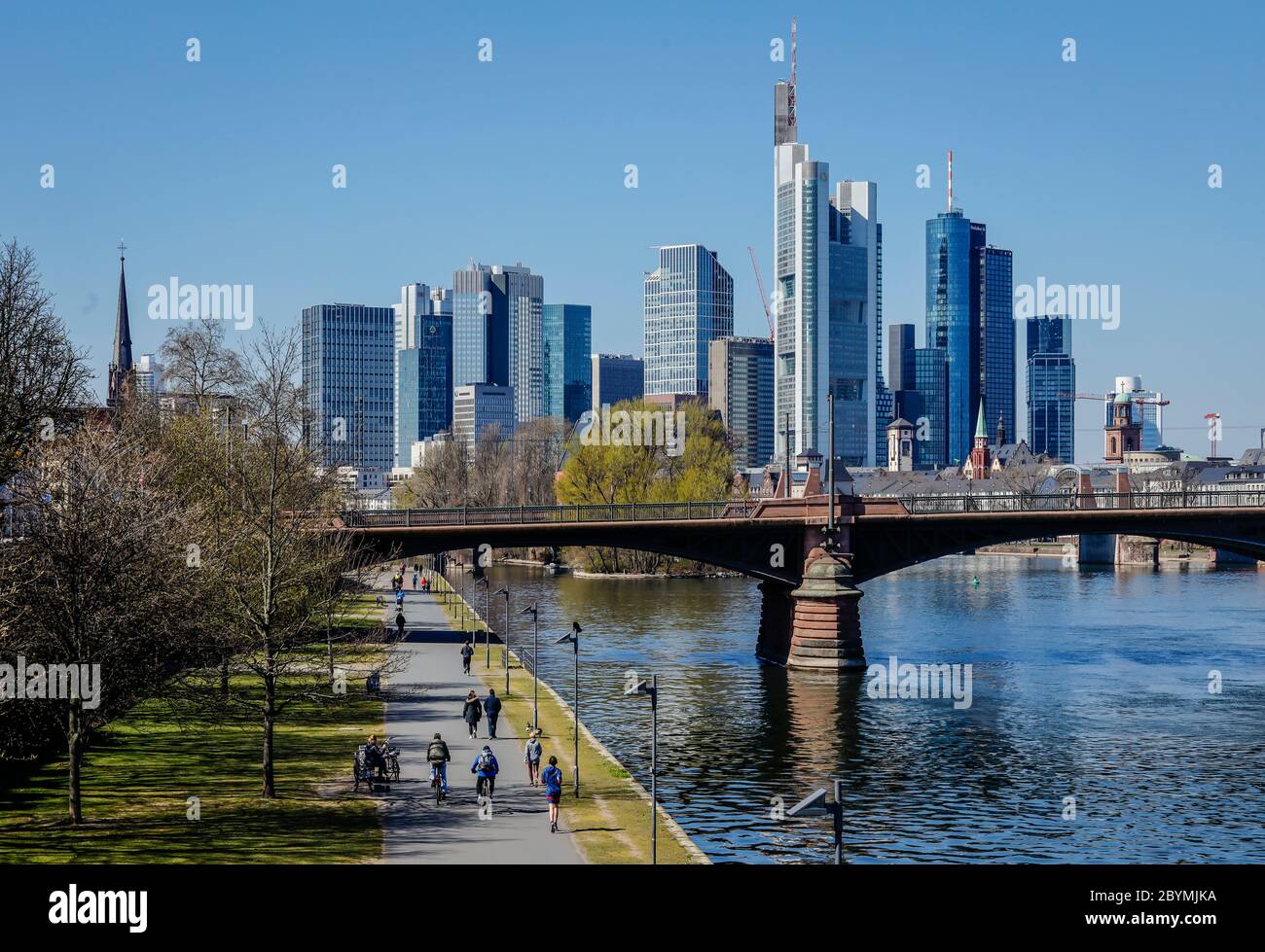 01.04.2020, Frankfurt am Main, Hesse, Germany - Walkers on the banks of the Main during the Corona crisis with a ban on contact, in the back skyline o Stock Photo