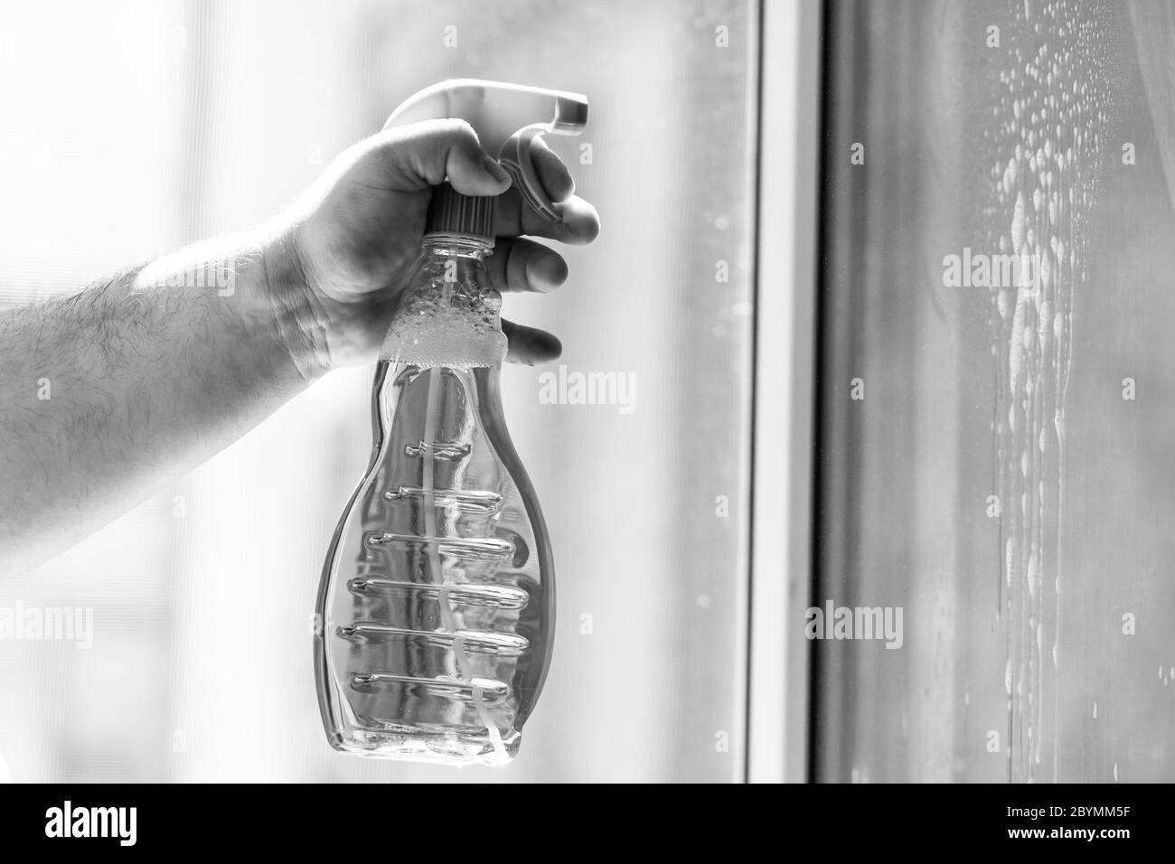 Man cleaning window using window cleaning squeegee and cleaning sprayer