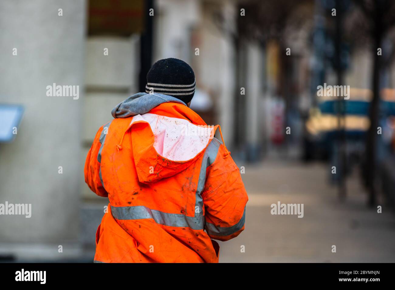Back view of construction worker wearing dirty reflective jacket preparing for work. Bucharest