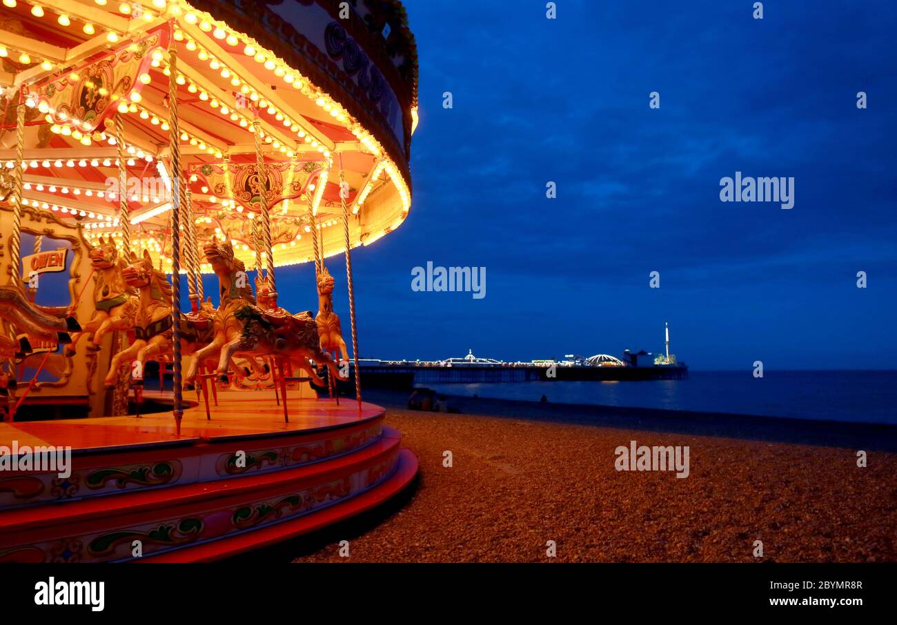 A beach front fairground ride with the Palace Pier. The West Sussex Brighton town seafront. The fairgrounds, bars, clubs and nightlife makes the city Stock Photo