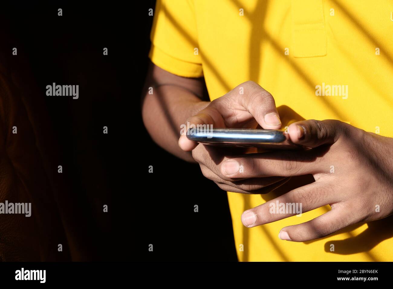 young man in yellow shirt using smart phone  Stock Photo