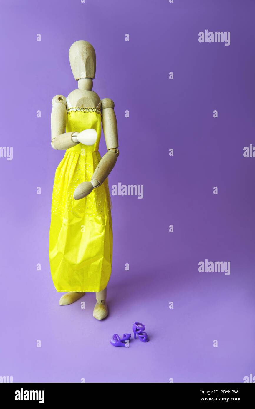 Concept of gender dysphoria and transgenders. Gestalta wearing a yellow dress, woman shoes on purple background. Place for text. Stock Photo