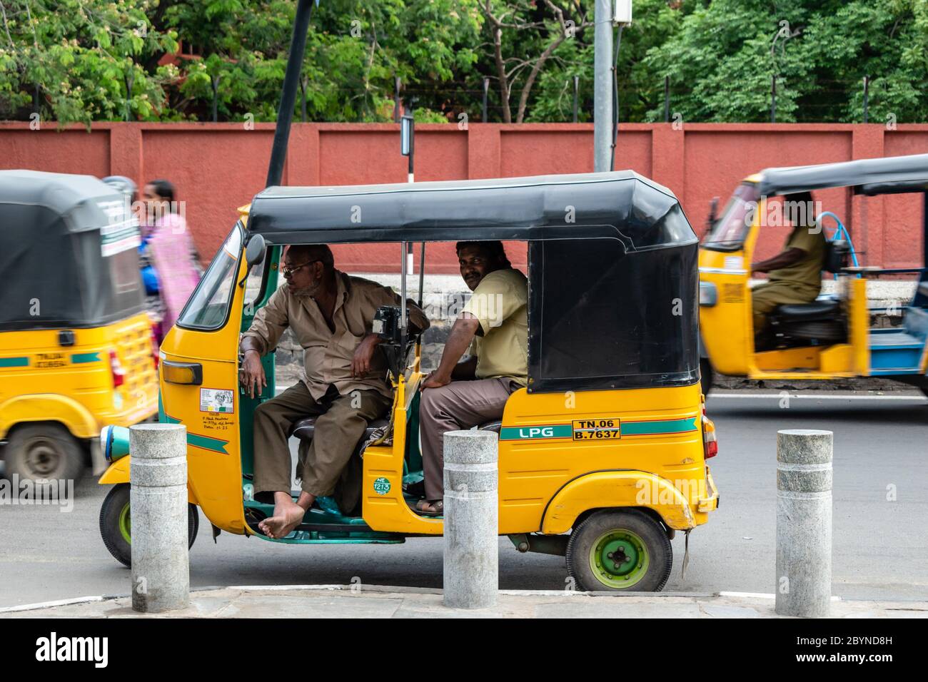 Chennai, Tamil Nadu, India - August 2018: Two auto rickshaw drivers idling inside a vehicle parked by the roadside. Stock Photo
