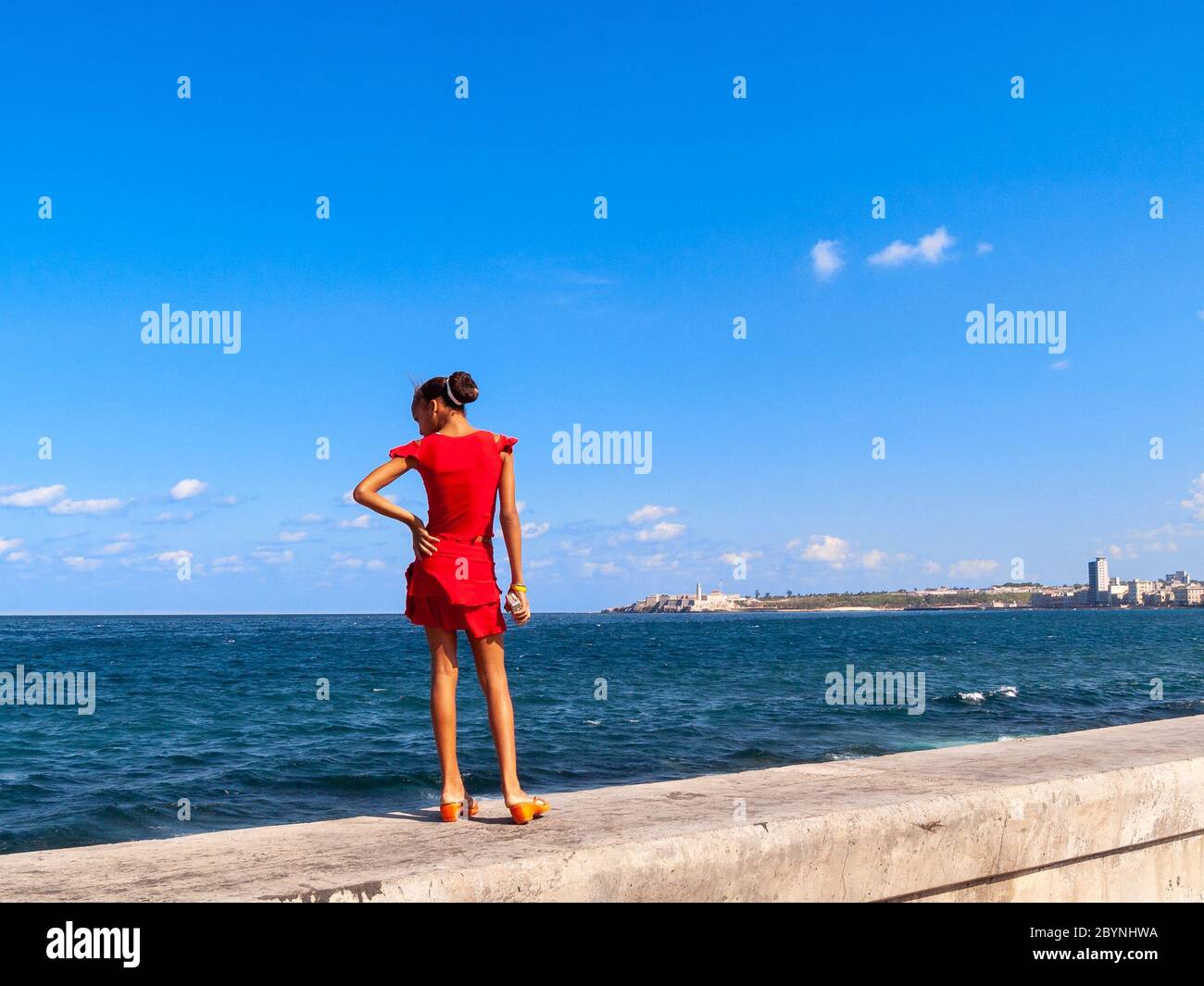 Young girl standing on the wall of El Malecon, Havana, Cuba Stock Photo