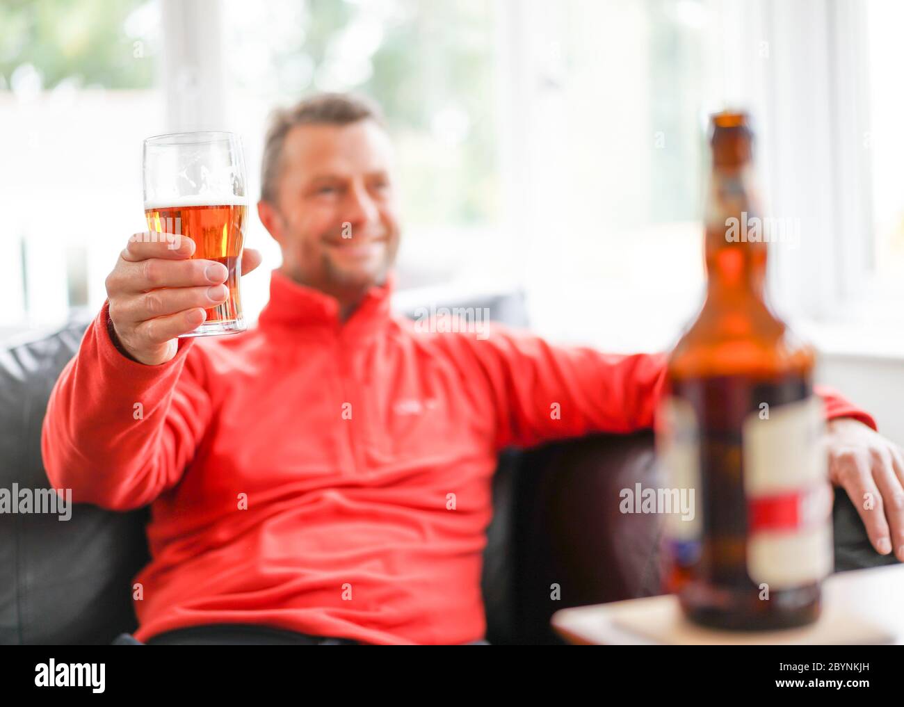 Cheers! Close up of isolated smiling man relaxing at home drinking beer