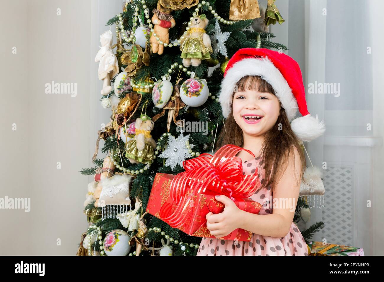 Happy little girl with christmas present smiling Stock Photo - Alamy