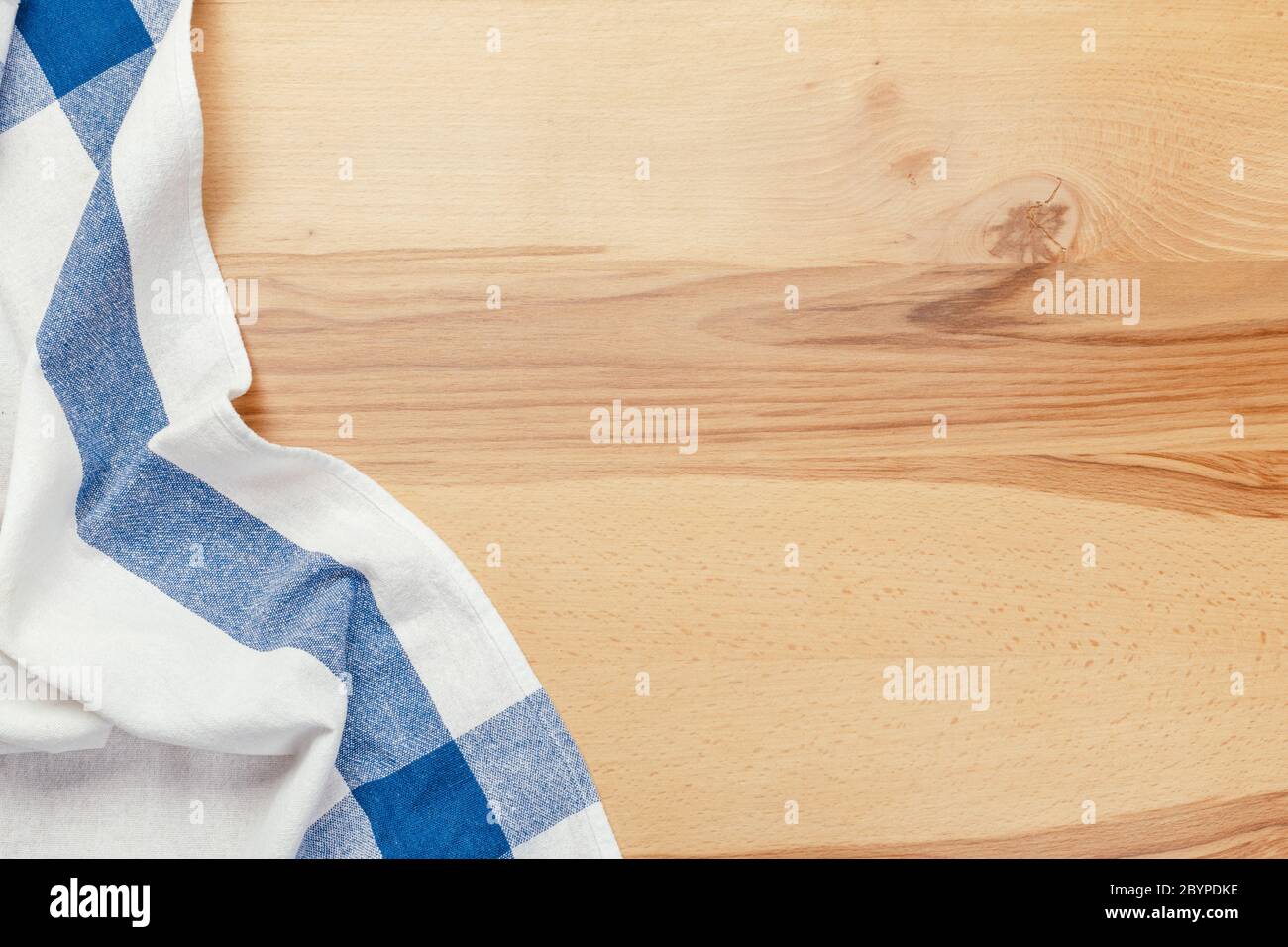 Top view on a wooden table with a linen kitchen towel or textile napkin. a tablecloth on a countertop made of old wood. Stock Photo