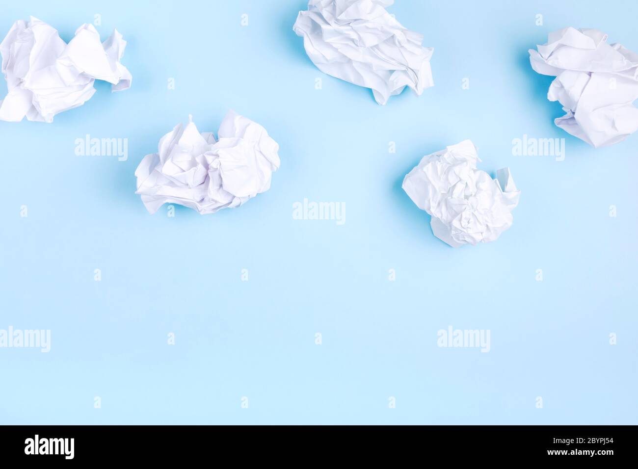 Crumpled white paper in the form of clouds on blue background. Concept head in clouds. Top view. Copy space Stock Photo
