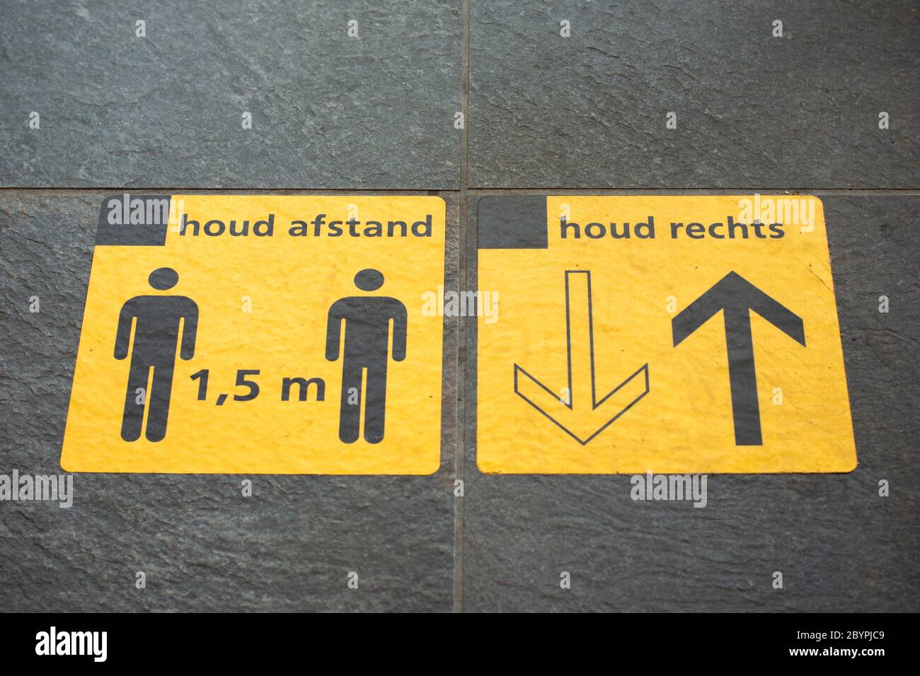 Two yellow sticker signs on platform railway station reminding people to keep social distancing 1,5 meter and to walk on the right side Stock Photo