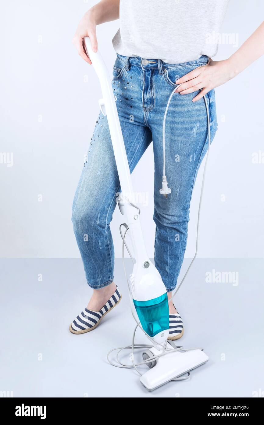 Concept wireless vacuum cleaners, wire interferes, inconvenience. Girl stands next to vacuum cleaner on the floor long tangled wire Stock Photo