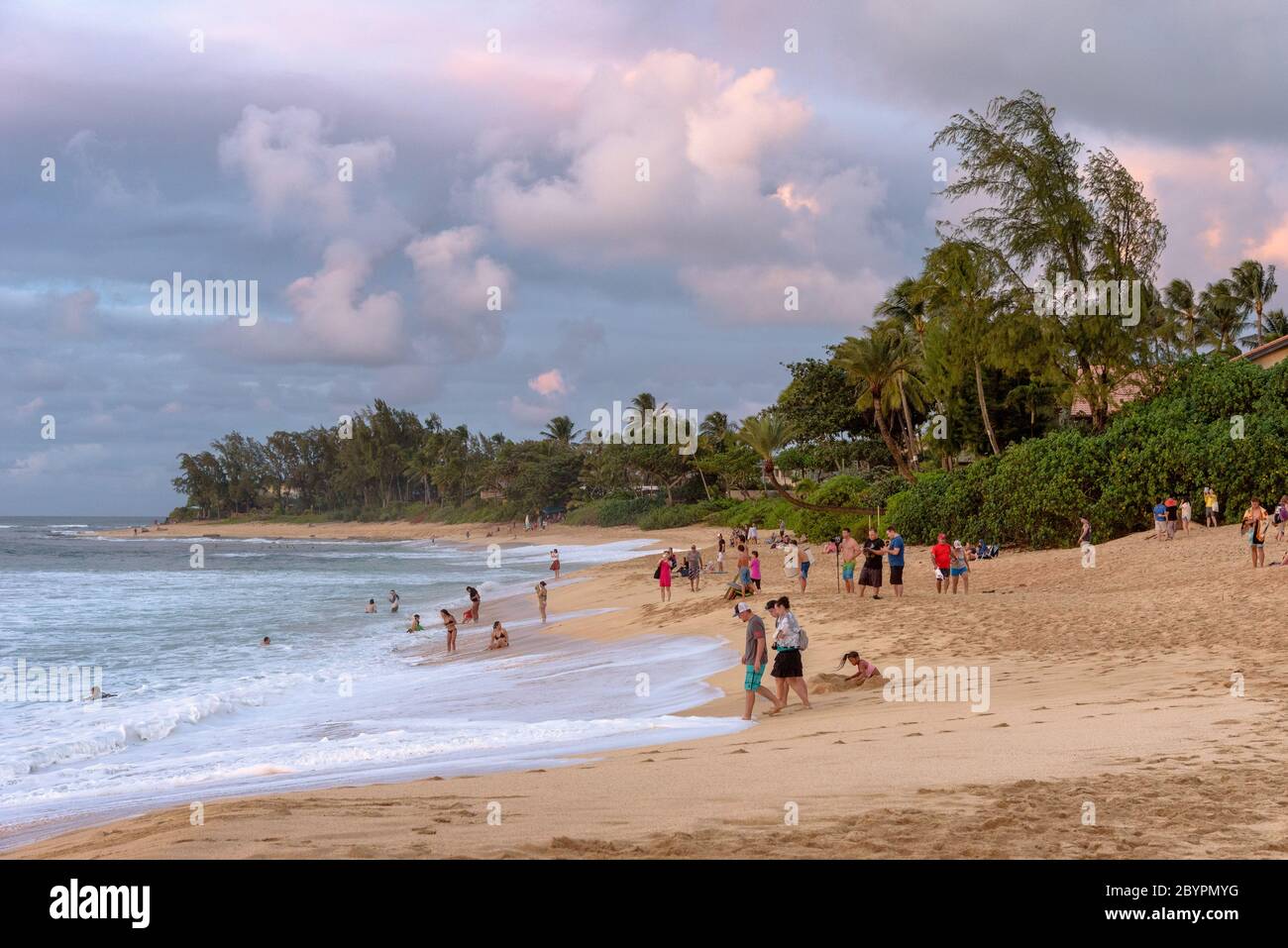 People on the beach at dusk at Sunset Beach Park on the north shore of Oahu, Hawaii Stock Photo