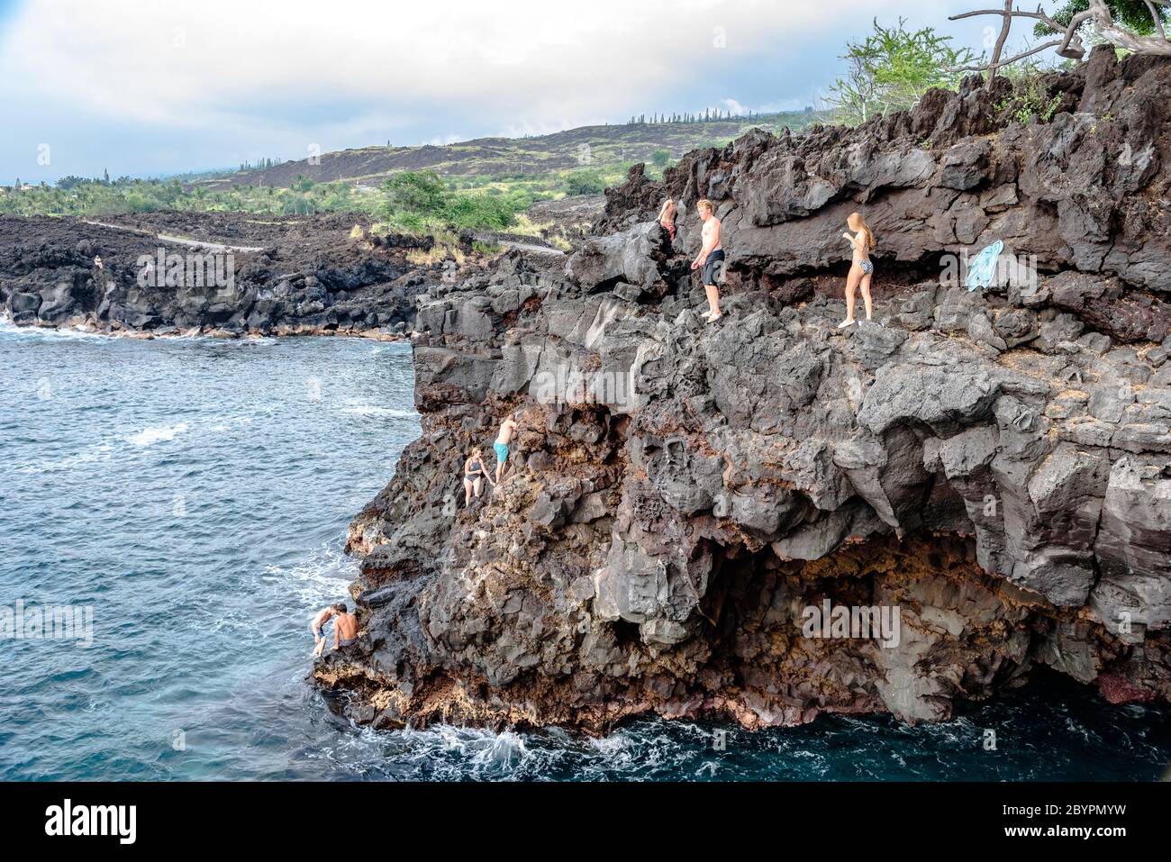 People cliff jumping into Keauhou Bay at the End of the World on the Big Island of Hawaii Stock Photo