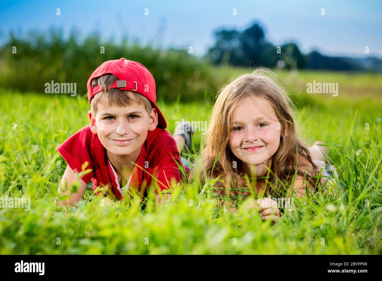 Cut boy and a girl are resting on the green grass in summer Stock Photo