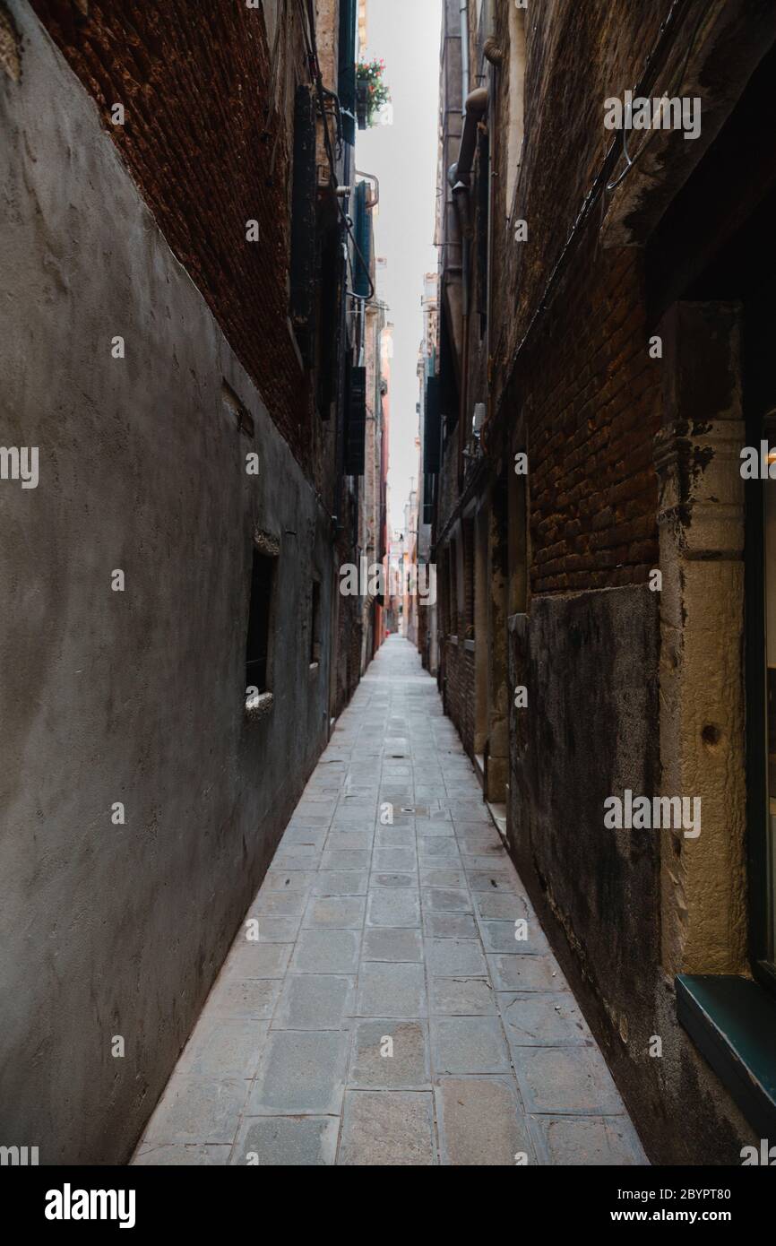 An empty alley with brown brick walls in daylight Venice, Italy. Light at the end of the tunnel. Stock Photo