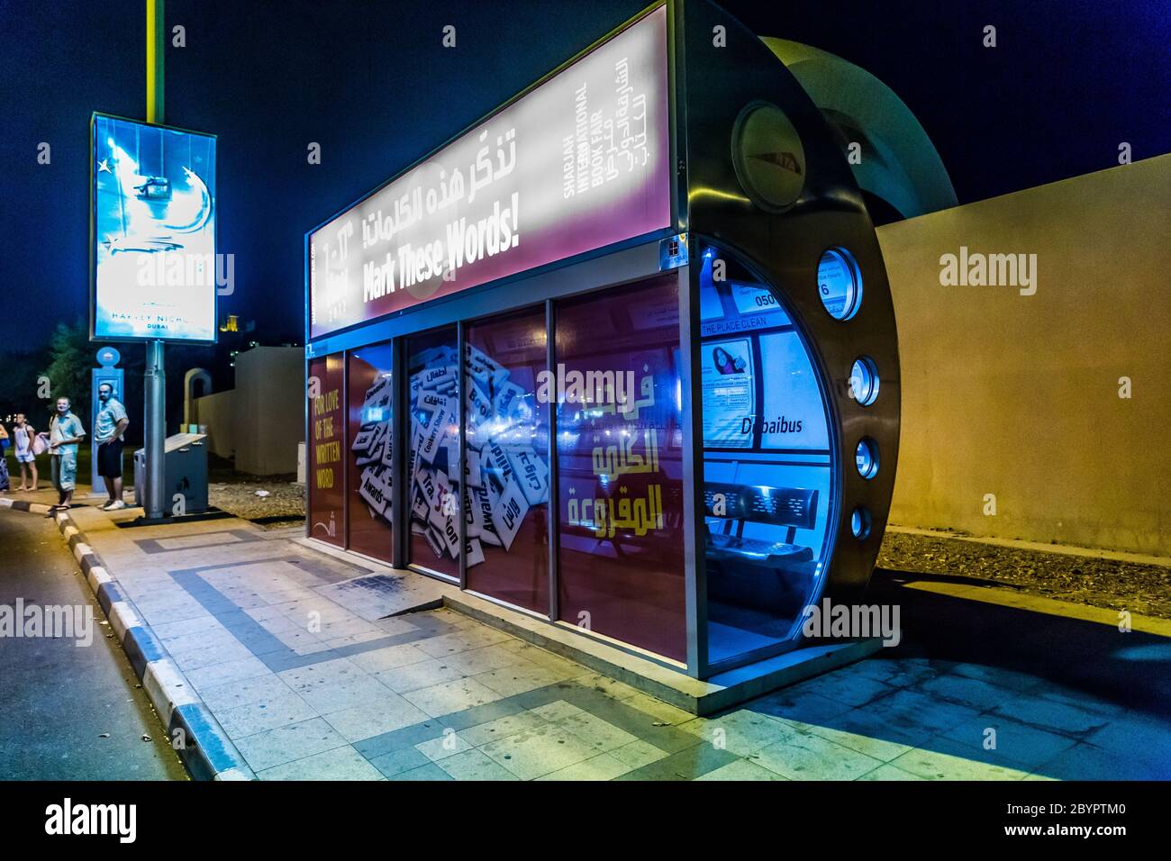 An air conditioned bus stop in Dubai with a tourist reflection in the