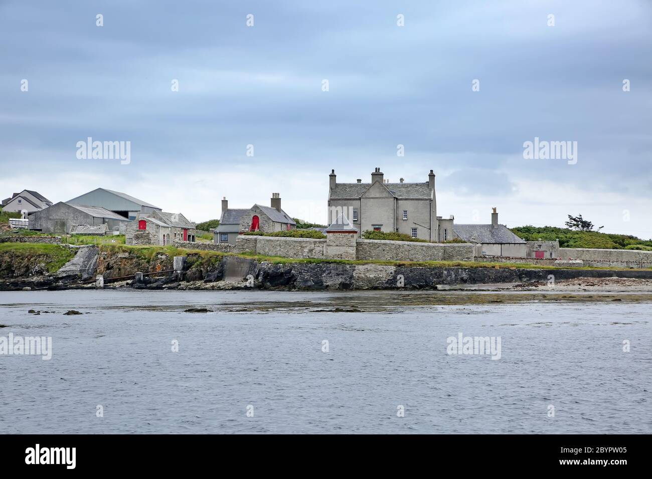 Coastline with pebbles & boulders and the Sandsayre Pier on a grey summer day, Sandwick, Shetland Islands, Scotland. Stock Photo