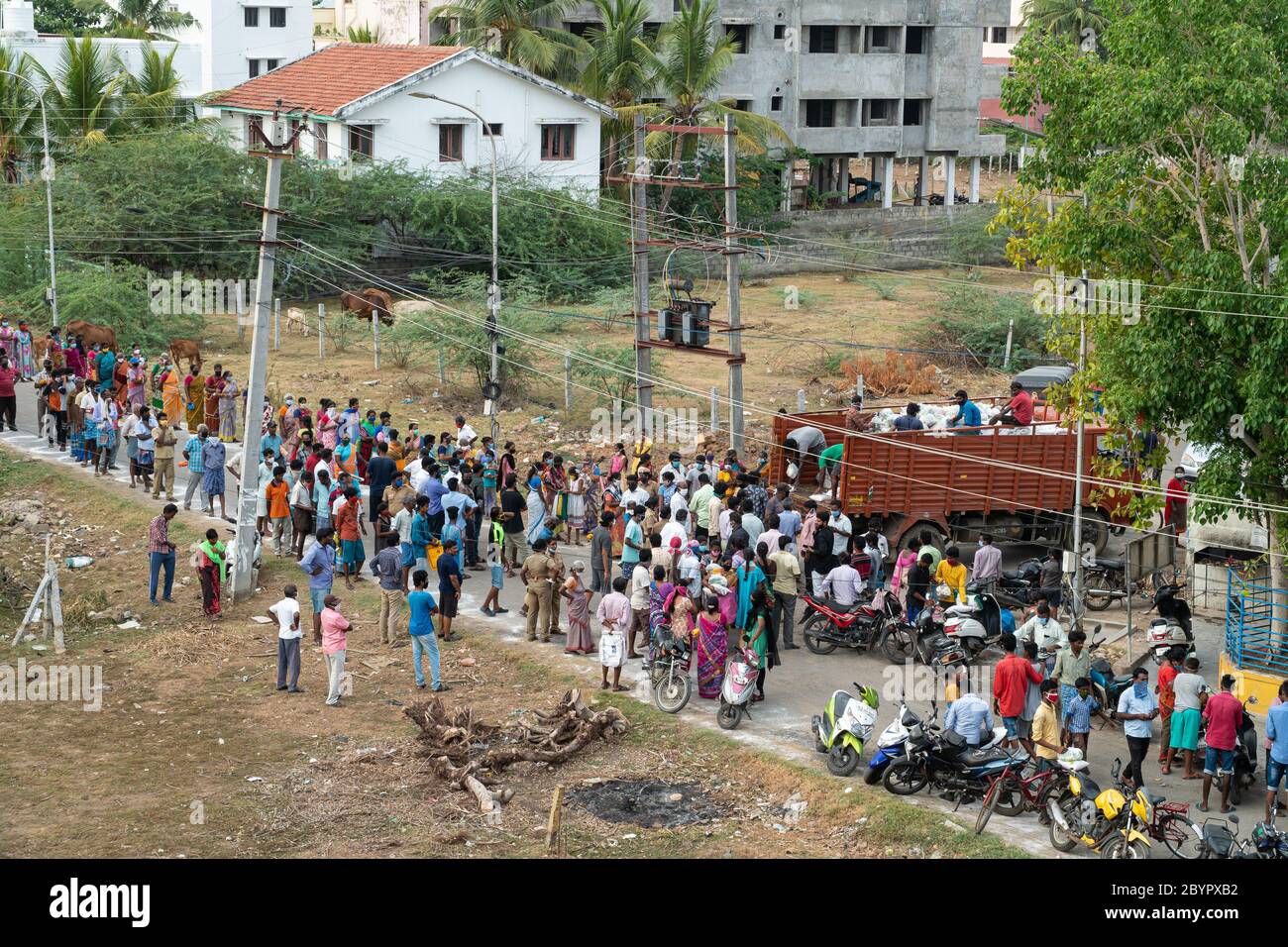 A group of people gather to receive free groceries and rice despite concerns about the spread of COVID-19. The crowd is watched by police, yet some pe Stock Photo