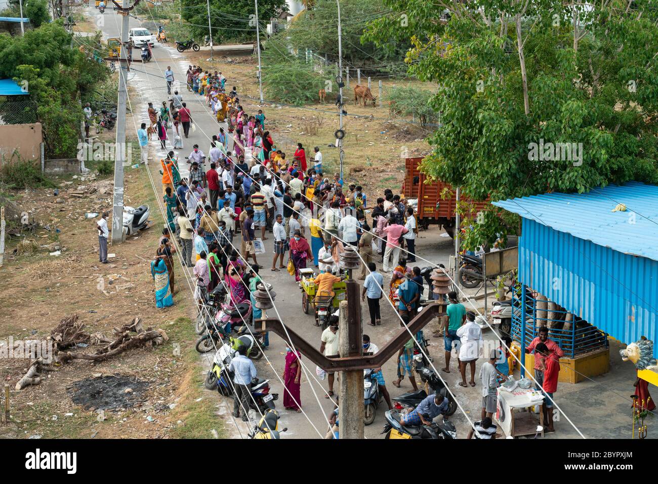 A group of people gather to receive free groceries and rice despite concerns about the spread of COVID-19. The crowd is watched by police, yet some pe Stock Photo