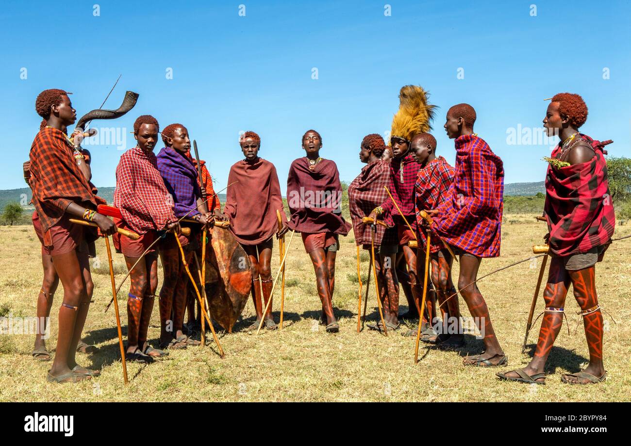 Group of young Masai warriors in traditional clothes and weapons are dancing their ritual dance in the savannah. Tanzania, East Africa. Stock Photo