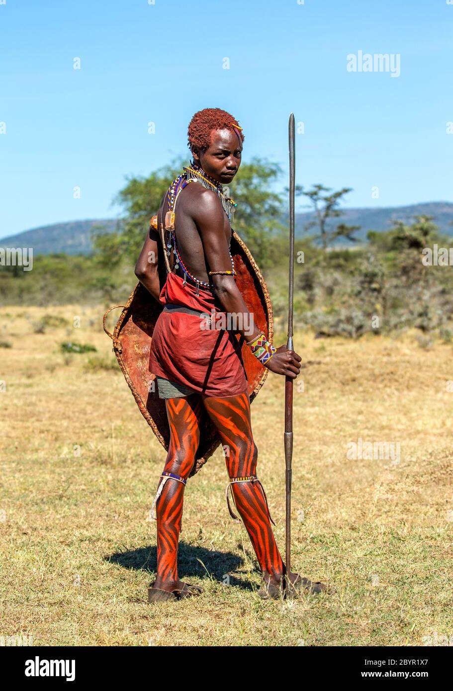 guerrier vetements masai Young Masai warrior is standing in the savannah in traditional