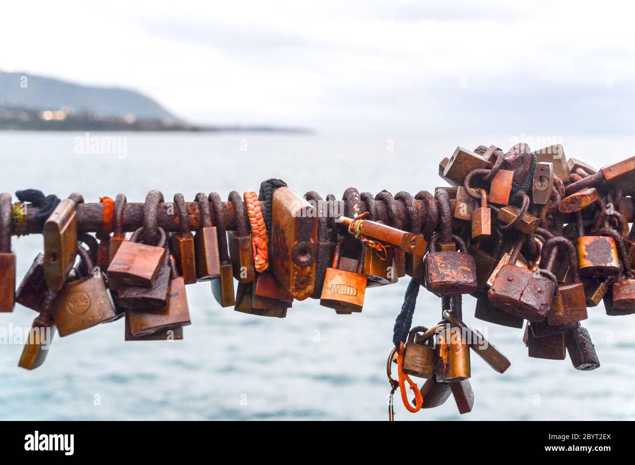 Rusty locks on a bridge, with the Mediterranean sea in the background Stock Photo