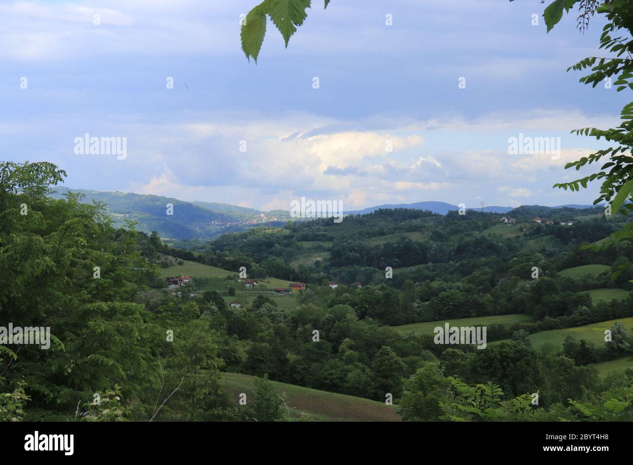 Dramatic spring mountain landscape of a beautiful green forest where small mountain villages can be seen in the distance located in unusually quiet Stock Photo