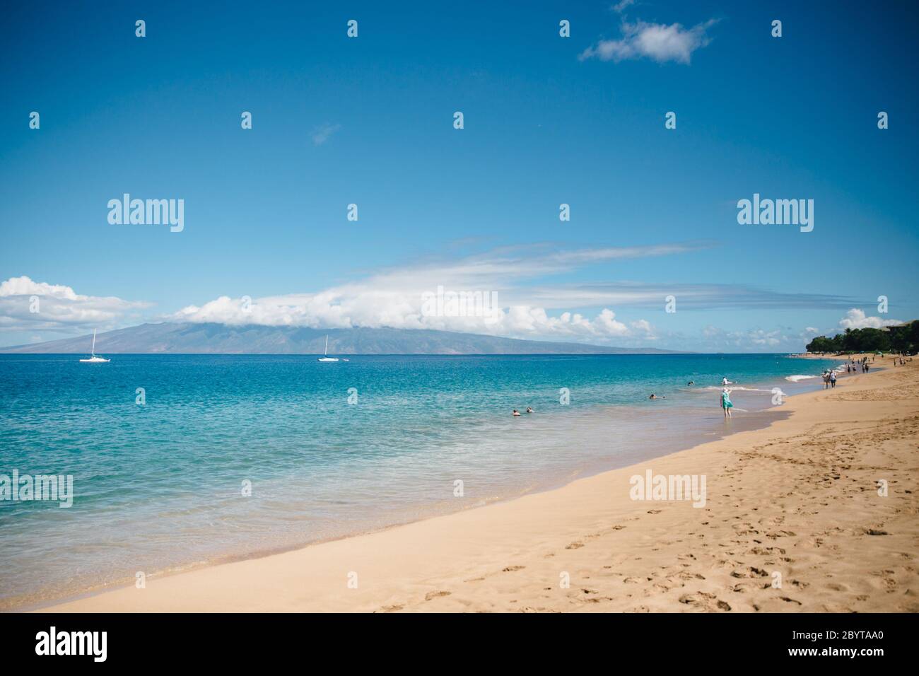 Clear Blue Waters of Kaanapali Beach on the Island of Maui, Hawaii during the daytime with a single person walking Stock Photo