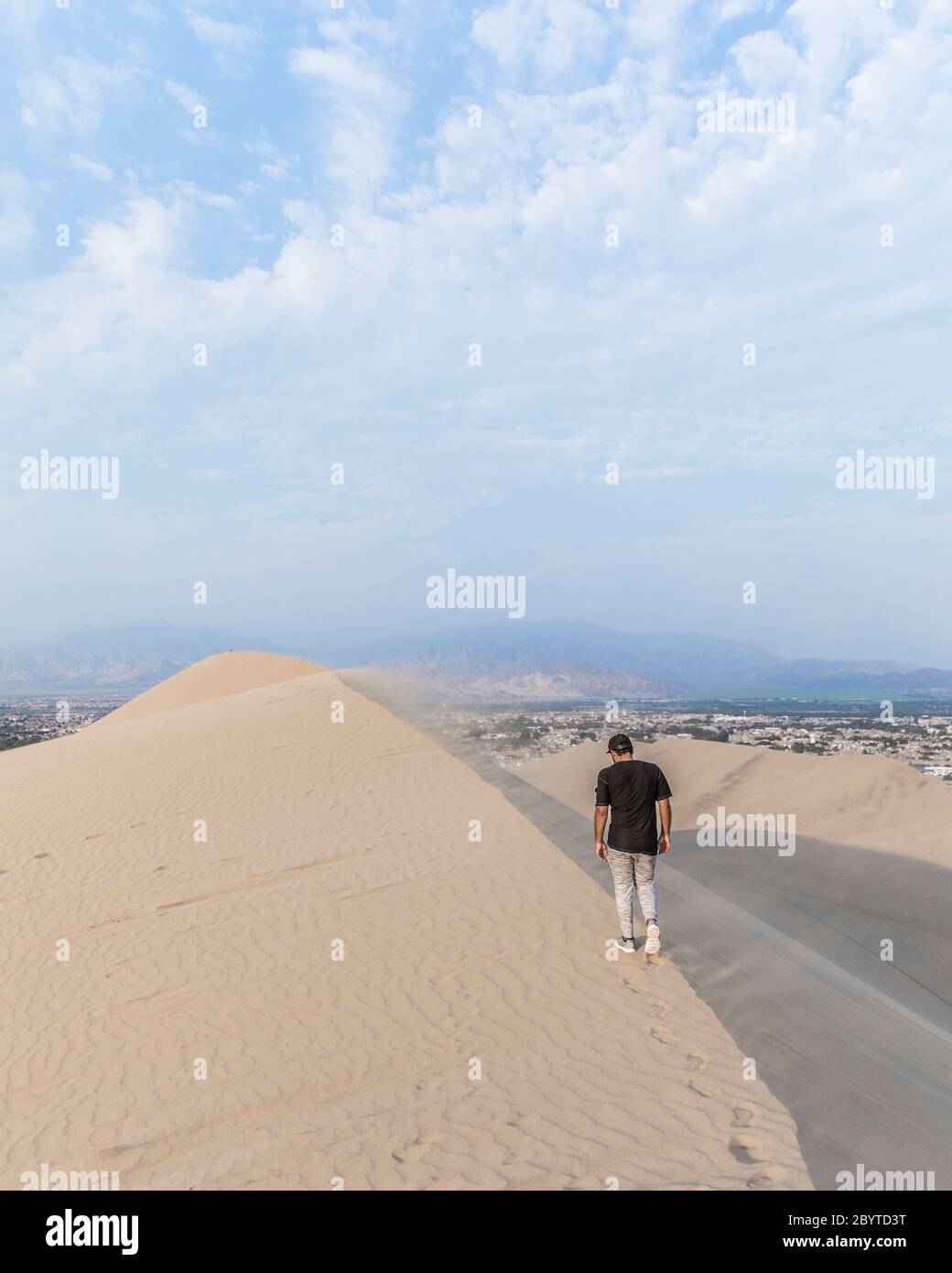 man walking on top of a dune and blue sky Stock Photo