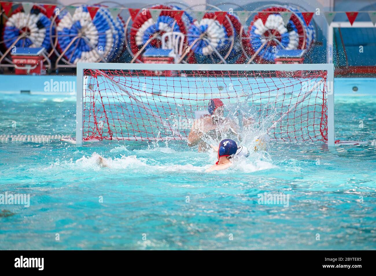 Water polo player in a swimming pool scoring goal splashing water Stock Photo