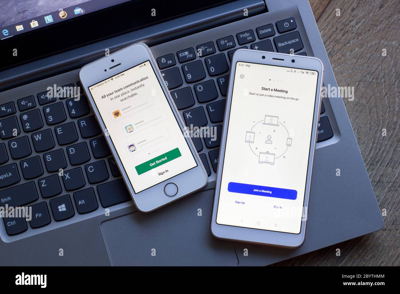 Team communication and collaboration tools login pages seen on smartphones. Left: Slack. Right: Zoom Cloud Meetings. Stock Photo
