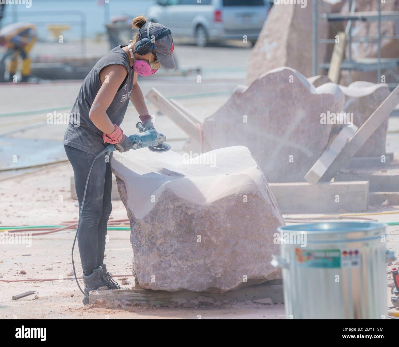 An artist works on a large block of stone at Sculpture Saint John, a sculpture symposium that hosts artists from around the world. Stock Photo