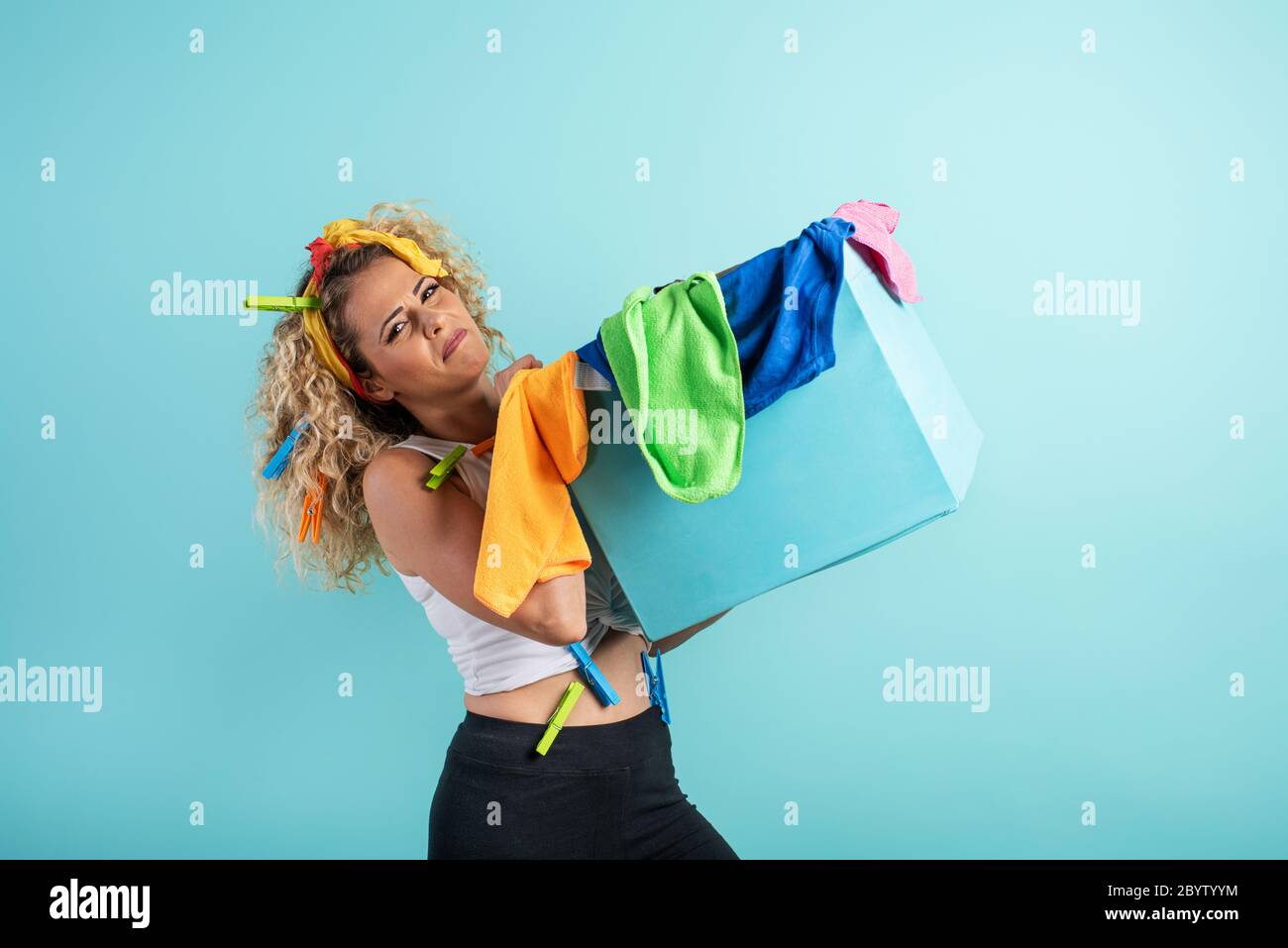 Tired housewife full of clothes and cloths to clean. cyan background Stock Photo