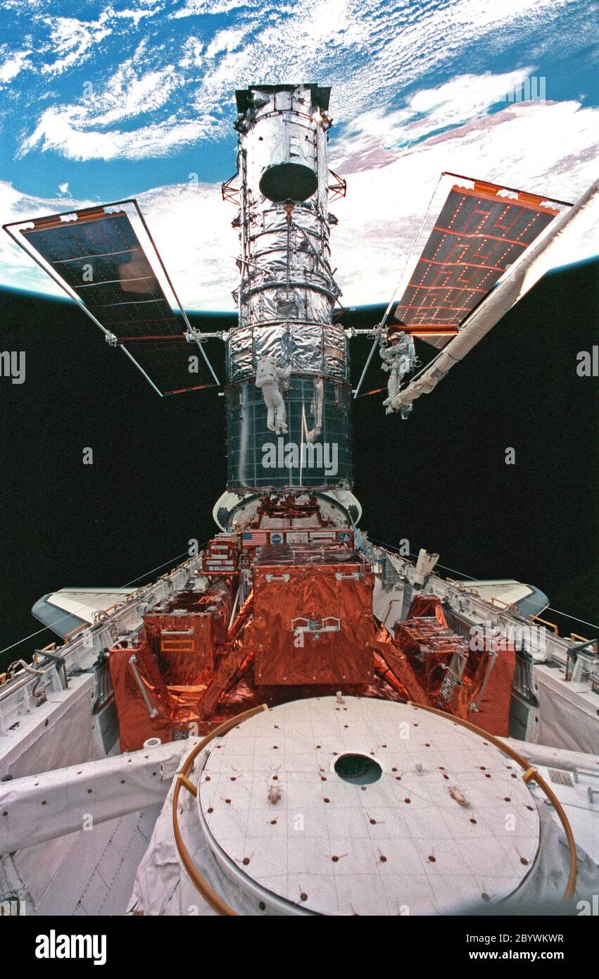 STS082-326-020 (17 Feb. 1997) --- This wide shot of the Hubble Space Telescope (HST) in Discovery's cargo bay, backdropped against Australia, was taken during the fifth space walk added to complete servicing of the orbiting observatory. Astronauts Steven L. Smith (center frame) and Mark C. Lee (on robot arm) are conducting a survey of the hand rails on HST. In foreground is the hatchway that connects to Discovery's shirt sleeve environment of the crew cabin. Stock Photo