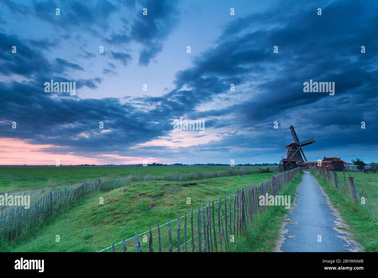 path to windmill in clouded dusk Stock Photo
