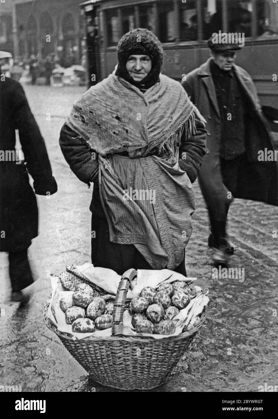 A woman selling pączki (filled doughnuts) in a street in Warsaw ca. December 1934 Stock Photo