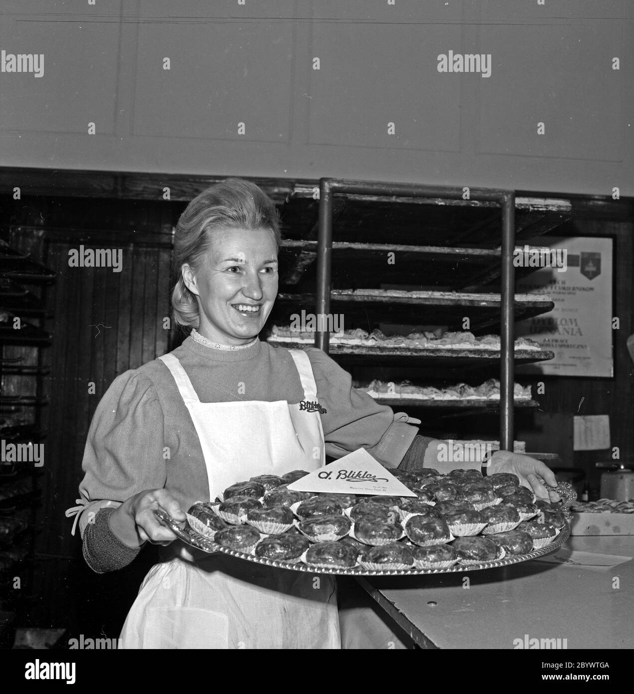 A woman carrying a platter of pączki (filled doughnuts) at Blikle pastry shop in Warsaw ca. 1969-1978 Stock Photo