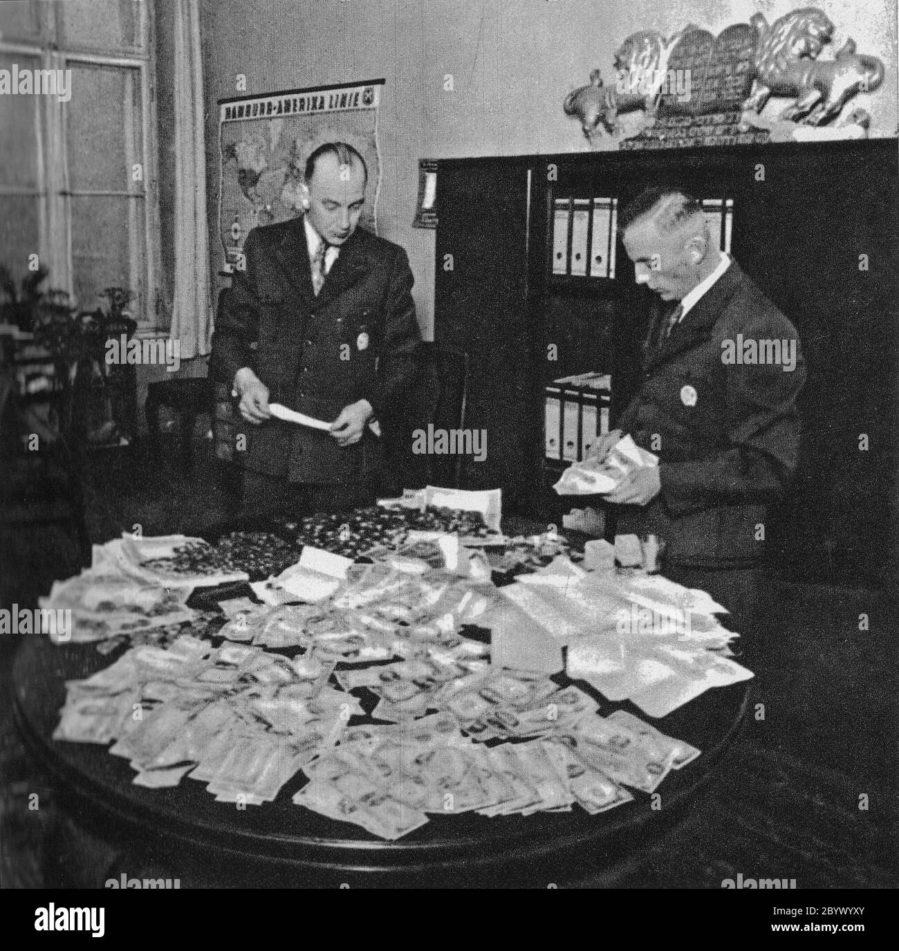 Preparation for shipment to Berlin of transport of gold coins and foreign currency stolen from Jews in Litzmannstadt Ghetto. Hans Biebow, first from the right ca. 1941-1943 Stock Photo