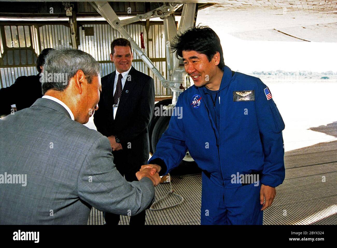 STS-87 Mission Specialist Takao Doi, Ph.D., of the National Space Development Agency (NASDA) of Japan greets a NASDA official shortly after the orbiter Columbia returned to KSC, touching down on Runway 33 at KSC's Shuttle Landing Facility. STS-87 concluded its mission with a main gear touchdown at 7:20:04 a.m. EST Dec. 5, drawing the 15-day, 16-hour and 34-minute-long mission of 6.5 million miles to a close. Also onboard the orbiter were Commander Kevin Kregel; Pilot Steven Lindsey; Mission Specialists Winston Scott and Kalpana Chawla, Ph.D.; and Payload Specialist Leonid Kadenyuk of the Natio Stock Photo