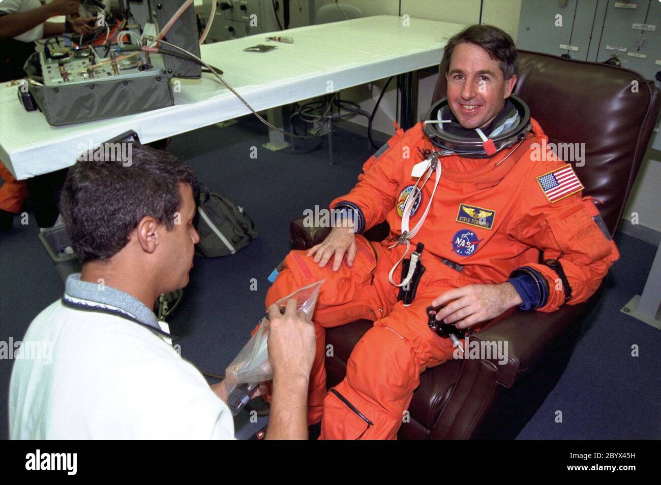 STS-85 Mission Specialist Stephen K. Robinson smiles as he is assisted with his ascent/reentry flight suit by a suit technician in the Operations and Checkout (O&C) Building. He has been a NASA employee since 1975 and has worked at Ames and Langley Research Centers. Robinson holds a doctorate in mechanical engineering and is a licensed pilot. He will assist Mission Specialist Robert L. Curbeam, Jr. with the Cryogenic Infrared Spectrometers and Telescopes for the Atmosphere-Shuttle Pallet Satellite-2 (CRISTA-SPAS-2) free-flyer and conduct Comet Hale-Bopp observations with the Southwest Ultravio Stock Photo